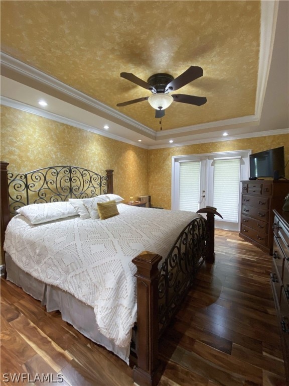 bedroom featuring ornamental molding, a tray ceiling, ceiling fan, and dark wood-type flooring