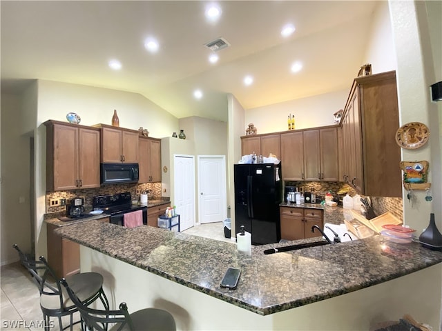 kitchen with dark stone counters, black appliances, sink, vaulted ceiling, and kitchen peninsula