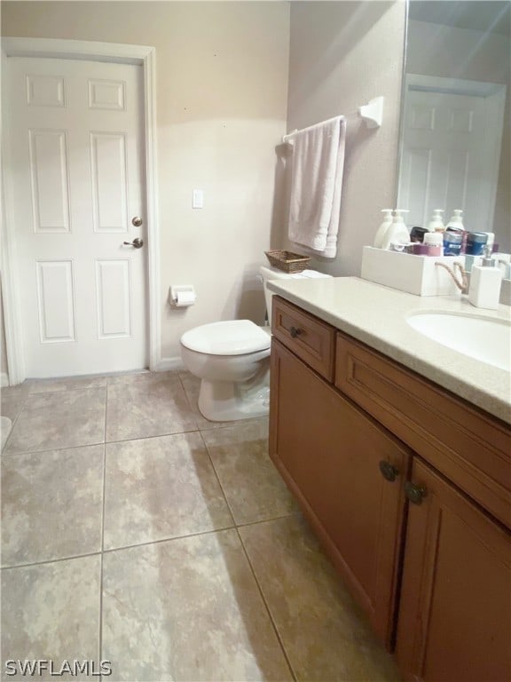 bathroom with toilet, vanity, and tile patterned floors