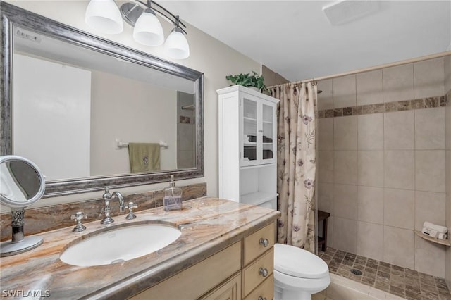 full bathroom with toilet, tiled shower, and vanity