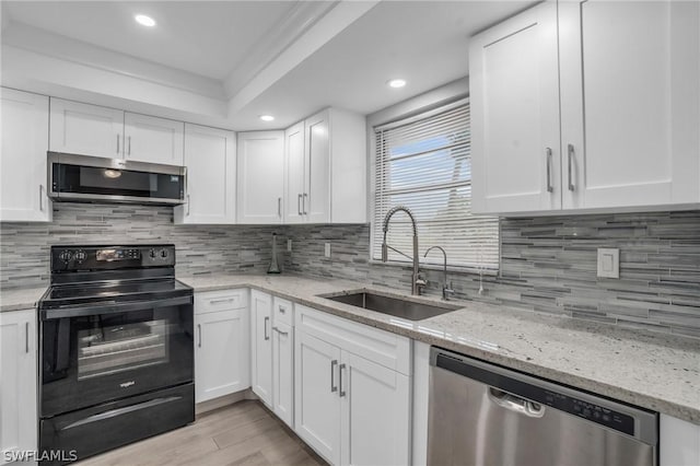 kitchen featuring sink, light wood-type flooring, light stone countertops, appliances with stainless steel finishes, and white cabinetry