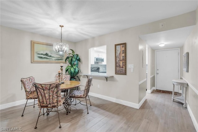 dining space with an inviting chandelier, wood finished floors, and baseboards