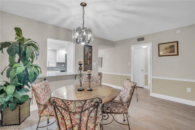 dining area with light hardwood / wood-style floors and an inviting chandelier