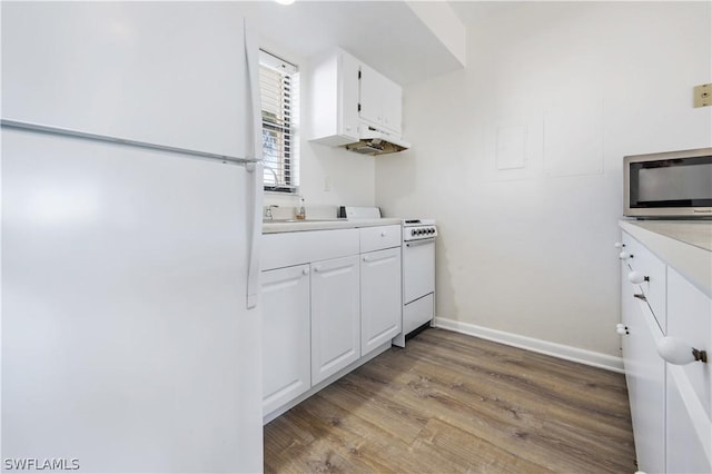 kitchen featuring white cabinets, white refrigerator, light wood-type flooring, and range