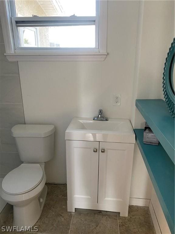 half bathroom featuring vanity, toilet, and a wealth of natural light