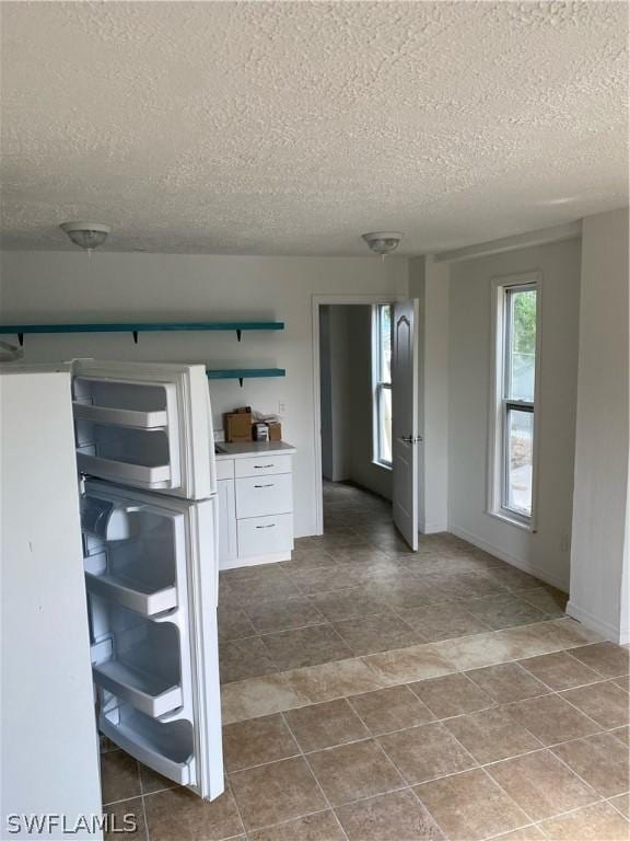 interior space with white cabinets, baseboards, and a textured ceiling