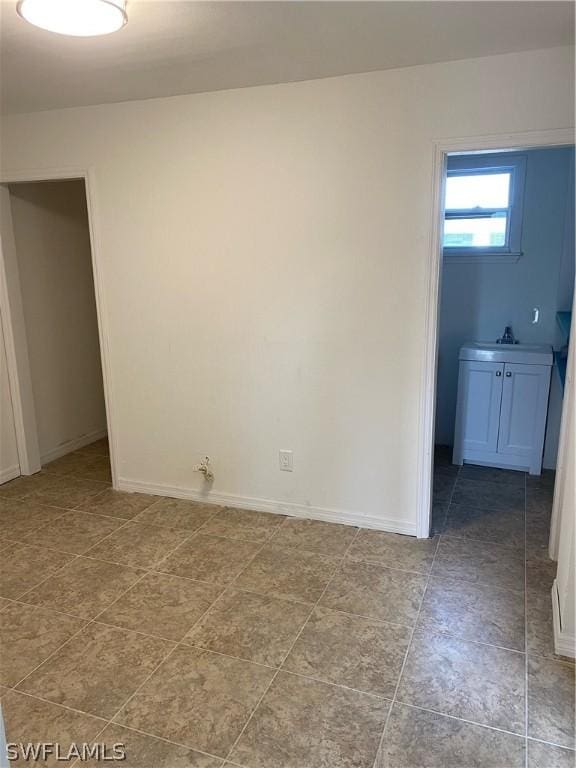 unfurnished room with baseboards and a sink