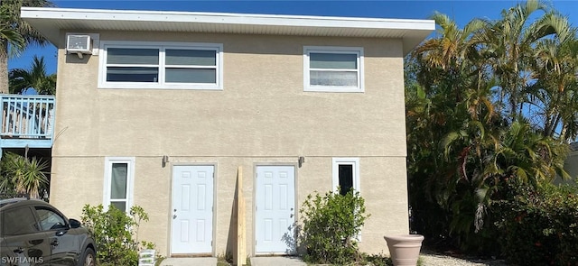 townhome / multi-family property with stucco siding and an AC wall unit