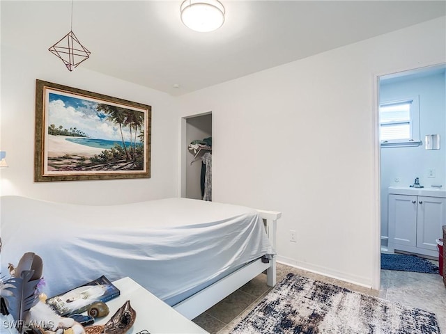 bedroom with a sink, baseboards, ensuite bathroom, and light tile patterned floors