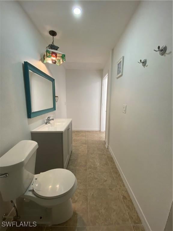 bathroom with baseboards, toilet, and vanity