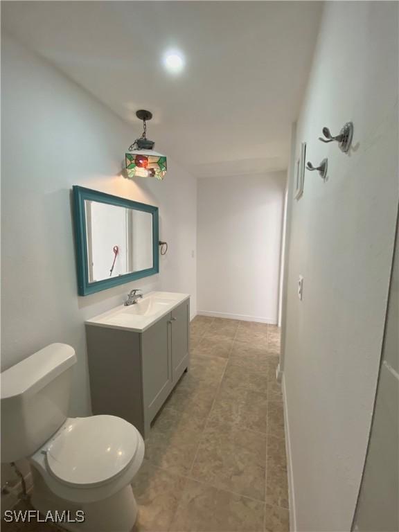 bathroom featuring toilet, vanity, and baseboards