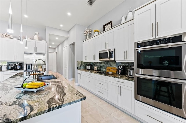 kitchen featuring appliances with stainless steel finishes, white cabinetry, and dark stone countertops