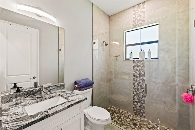 bathroom featuring vanity, an enclosed shower, and toilet