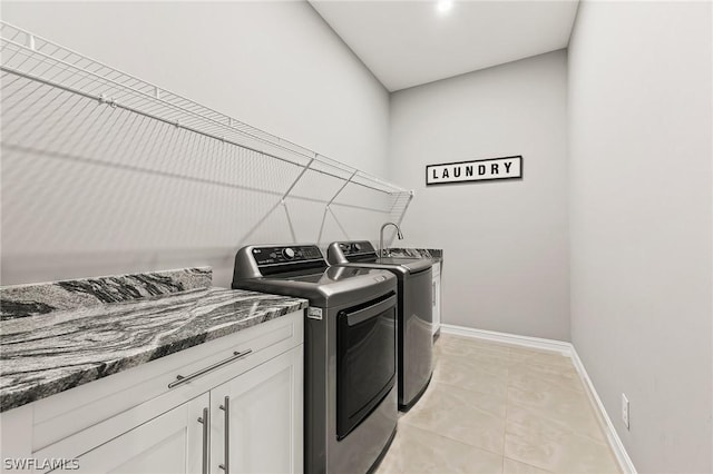 clothes washing area with cabinets, light tile patterned floors, and washing machine and dryer