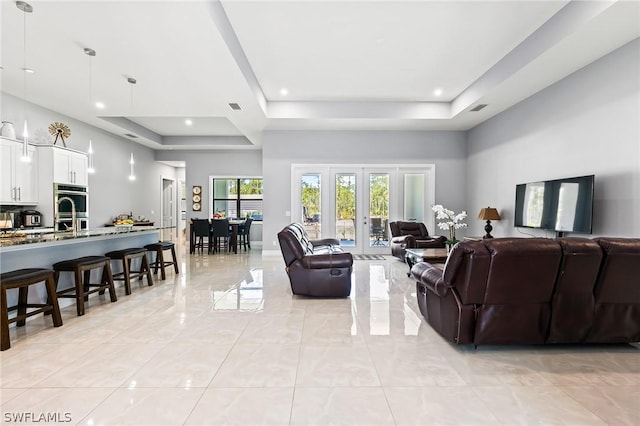 living room featuring a raised ceiling and french doors