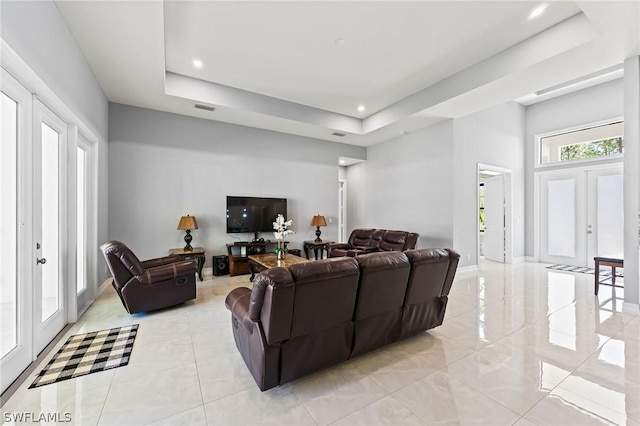 living room featuring french doors and a tray ceiling