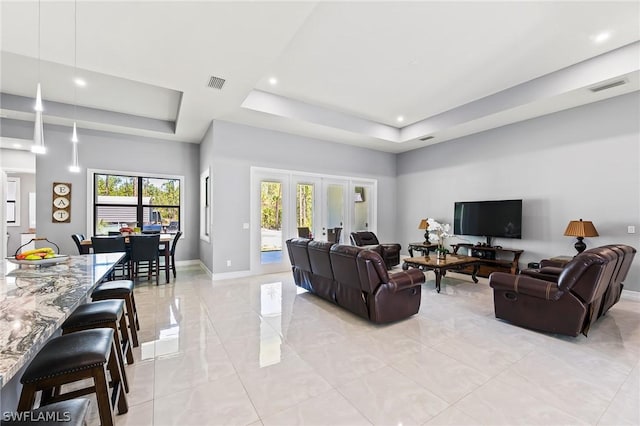 living room with a raised ceiling and french doors