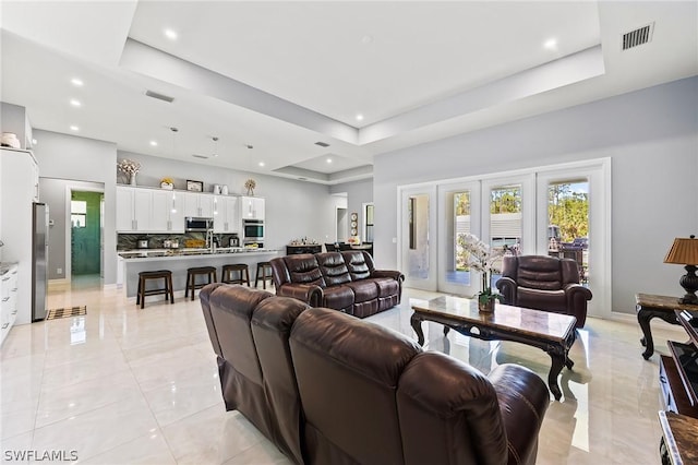 tiled living room with a raised ceiling and french doors