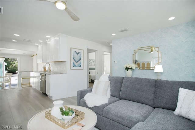 living room with ceiling fan, sink, and light wood-type flooring