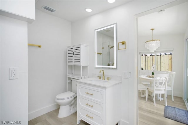 bathroom with hardwood / wood-style flooring, toilet, vanity, and an inviting chandelier