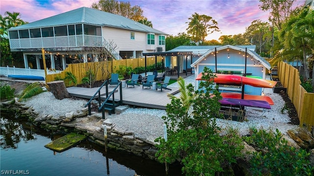 back house at dusk with a wooden deck and a sunroom