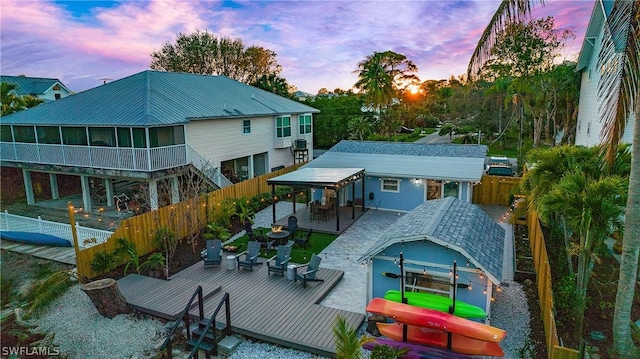 back house at dusk with a wooden deck and a sunroom