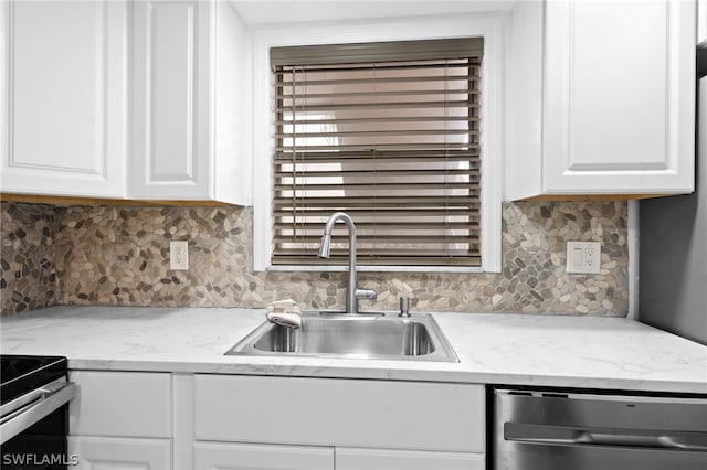 kitchen with appliances with stainless steel finishes, backsplash, white cabinetry, and sink