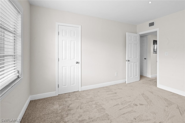 unfurnished bedroom featuring multiple windows and light colored carpet