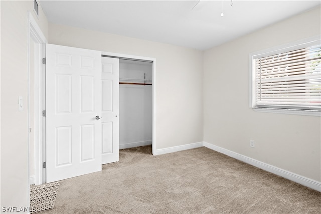 unfurnished bedroom with ceiling fan, a closet, and light colored carpet