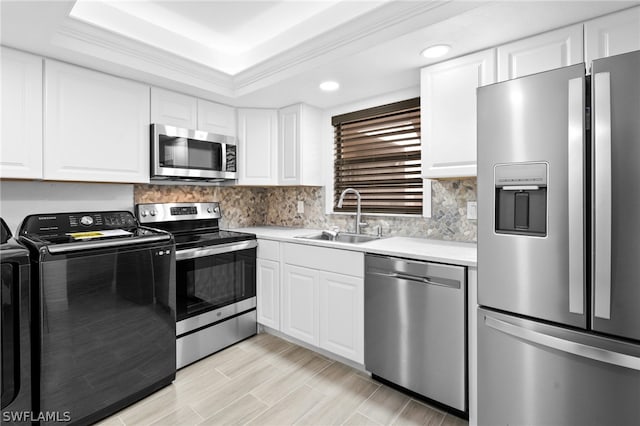 kitchen with stainless steel appliances, white cabinetry, washer / clothes dryer, and sink