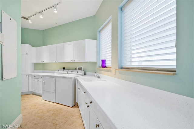 clothes washing area with rail lighting, sink, cabinets, light tile patterned floors, and washer and clothes dryer