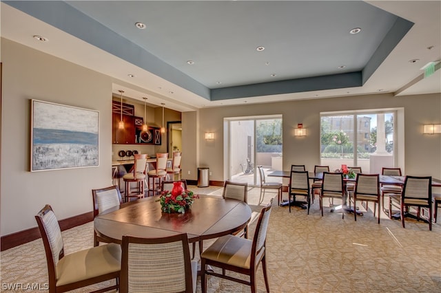 dining room featuring light carpet and a tray ceiling