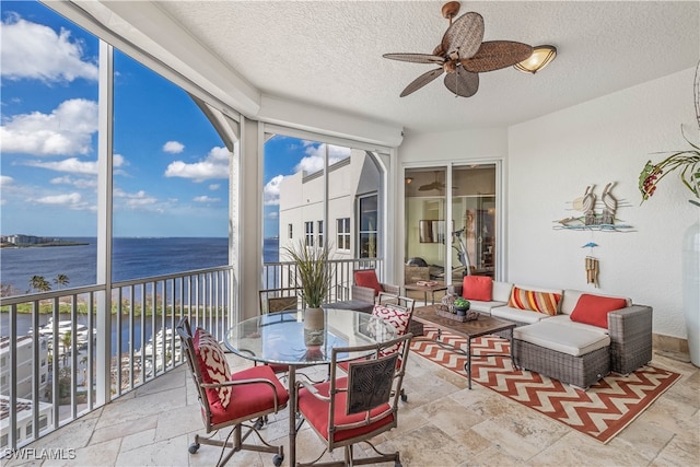 sunroom featuring a water view, ceiling fan, and a wealth of natural light