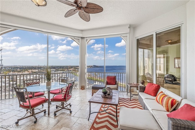 sunroom with a water view and ceiling fan