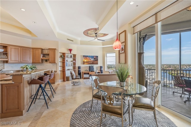 dining room featuring a raised ceiling, ornamental molding, sink, and ceiling fan