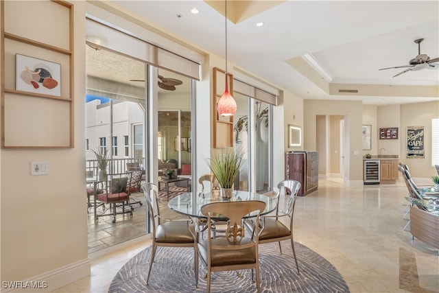 dining room with ceiling fan, plenty of natural light, beverage cooler, and a raised ceiling