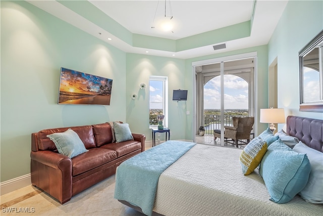 bedroom with access to exterior and a raised ceiling