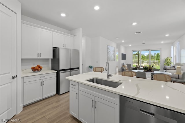 kitchen with white cabinets, light wood-type flooring, stainless steel appliances, and sink