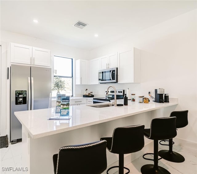 kitchen with appliances with stainless steel finishes, a breakfast bar, kitchen peninsula, and light tile patterned flooring