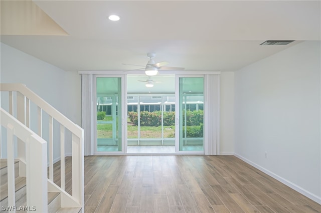 spare room featuring baseboards, visible vents, wood finished floors, stairs, and floor to ceiling windows