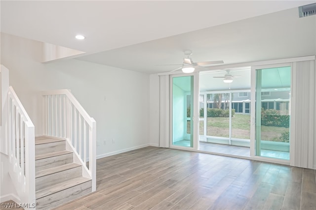 unfurnished room with baseboards, visible vents, stairway, wood finished floors, and recessed lighting