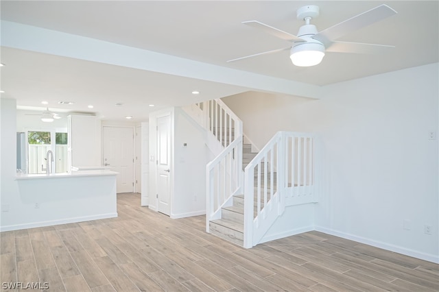 unfurnished room featuring light wood-style floors, stairway, and a ceiling fan