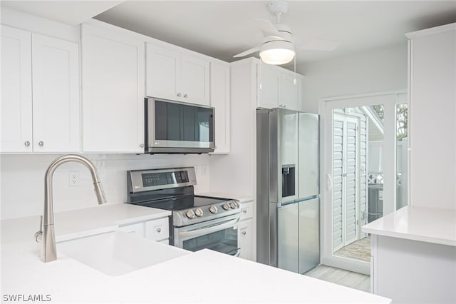 kitchen with light countertops, appliances with stainless steel finishes, white cabinets, a sink, and ceiling fan