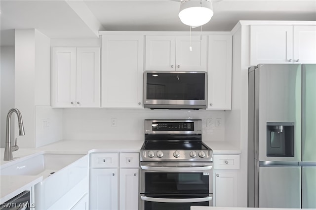 kitchen with light countertops, appliances with stainless steel finishes, a sink, and white cabinetry