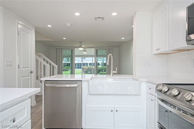 kitchen featuring visible vents, appliances with stainless steel finishes, white cabinets, and a sink