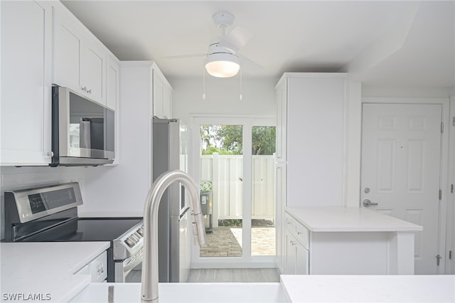 kitchen featuring light wood finished floors, light countertops, appliances with stainless steel finishes, a ceiling fan, and white cabinets