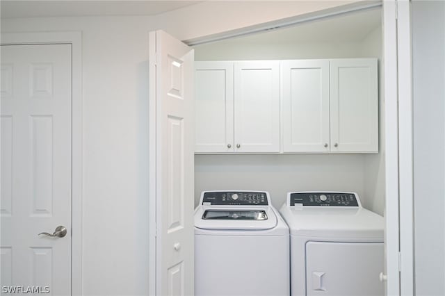 washroom featuring separate washer and dryer and cabinet space