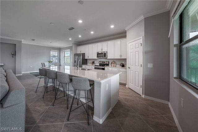 kitchen with stainless steel appliances, a center island with sink, a breakfast bar, white cabinets, and sink