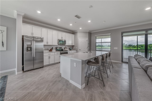 kitchen with a center island with sink, a kitchen bar, white cabinets, appliances with stainless steel finishes, and sink