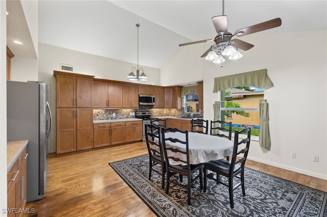 dining room with sink, high vaulted ceiling, ceiling fan, and light wood-type flooring